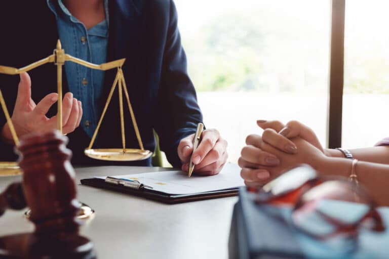 A lawyer reviewing legal documents with a woman during a consultation, with a gavel and scales of justice on the desk, suggesting legal guidance in a divorce case.